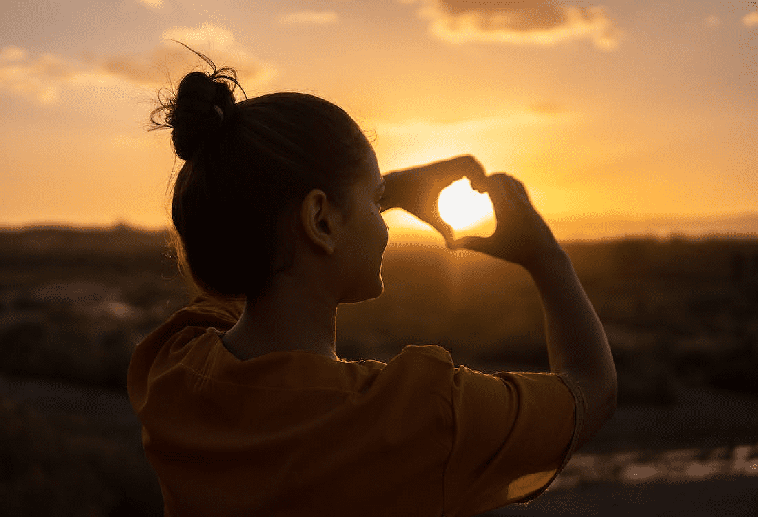 woman practicing self-love and gratitude by enjoying a sunset